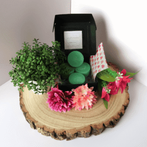 Citrus Garden Wax Melt inside an open black box, surrounded by flowers and a plant, all sitting on top of a wooden board.