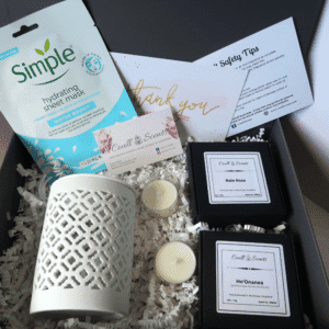 Pampering Wax Melt Gift Set showing Cut Out Wax Melt Burner, facial mask, 2 boxes of Wax Melts and 2 tealights, sitting on shredded paper in a grey box.