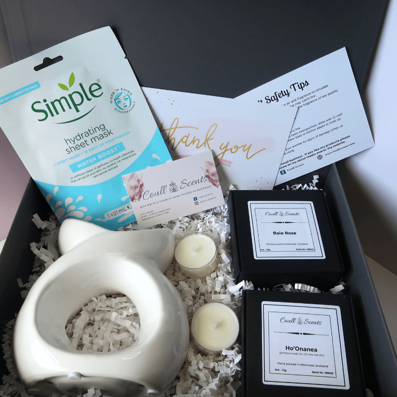 Pampering Wax Melt Gift Set showing Serenity Wax Melt Burner, facial mask, 2 boxes of Wax Melts and 2 tealights, sitting on shredded paper in a grey box.