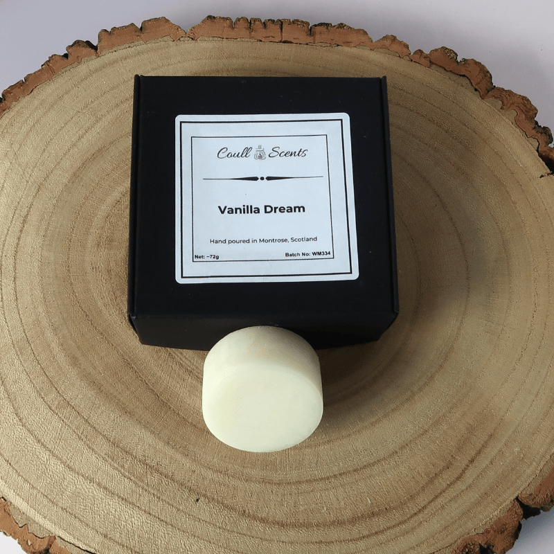 Vanilla Dream Wax Melt outside its black box, sitting on top of a wooden board.
