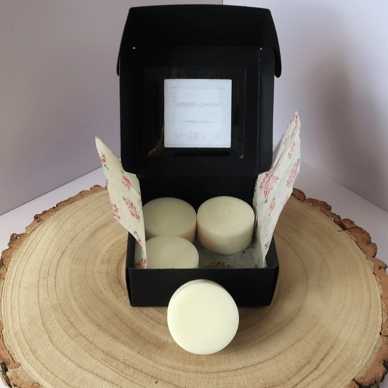 Vanilla Dream Wax Melt inside an open black box, sitting on top of a wooden board.
